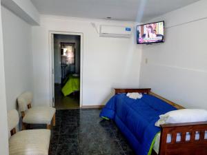 1 dormitorio con 1 cama y TV en la pared en Departamento Colón 2 en San Rafael