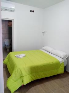 een groen bed in een witte kamer met een toilet bij Departamento Colón 2 in San Rafael