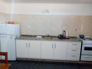 een keuken met witte kasten en een witte koelkast bij Departamento Colón 2 in San Rafael