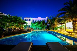 a swimming pool with palm trees and a building at Casa Di Roma in Parikia