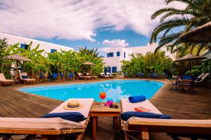 a pool with two chairs and a table next to a resort at Casa Di Roma in Parikia