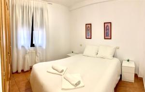 a bedroom with a white bed with two towels on it at APARTAMENTO ALAMILLO Alto in Chinchón