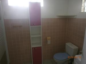 a bathroom with a toilet and a tiled wall at case créole in Pointe-Noire