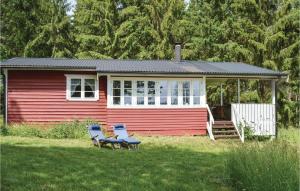 a small red house with two chairs in the yard at 1 Bedroom Cozy Home In Torup in Torup