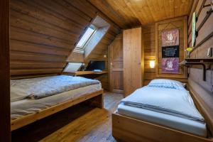 a bedroom with two beds in a wooden cabin at Penzion pod Lipou in Liptovský Ján