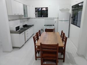 Il comprend une cuisine avec une table et des chaises en bois. dans l'établissement Apartamentos Praia do Sonho, à Palhoça