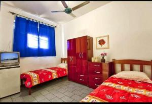 a bedroom with two beds and a tv in it at Residencial Potengy in Natal