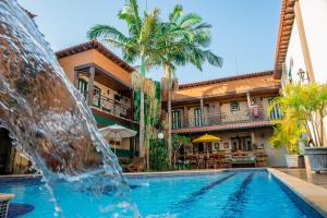 a pool with a fountain in front of a hotel at Tiradentes Village in Tiradentes