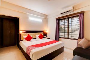 a bedroom with a bed with red pillows and a window at Aster Suites in Bangalore