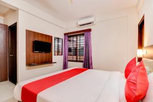 a bedroom with a bed and a tv on the wall at Aster Suites in Bangalore