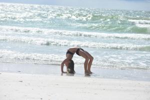 een vrouw in een bikini die voorover buigt op het strand bij Beachfront Bliss Villas in Clearwater Beach