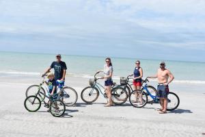 een groep mensen op het strand met fietsen bij Beachfront Bliss Villas in Clearwater Beach