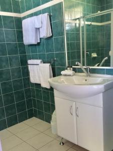Baño de azulejos verdes con lavabo y espejo en Bakery Park Motor Inn, en Tocumwal