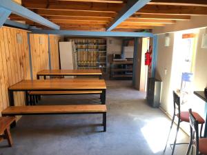 Habitación con 2 mesas de madera y nevera. en Hostel NIX en San Carlos de Bariloche