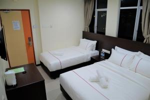 Habitación de hotel con 2 camas con sábanas blancas en DCozy Hotel en Perai