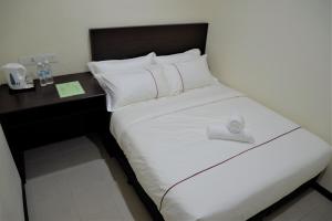 a bed in a hotel room with a desk at DCozy Hotel in Perai