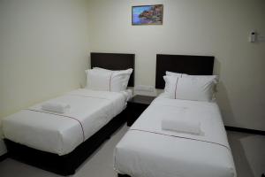 two beds in a hotel room with white sheets at DCozy Hotel in Perai