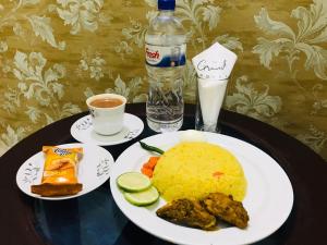 une table garnie de assiettes de nourriture et de boissons dans l'établissement The Grand Hotel BD, à Sylhet