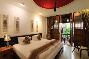 a bedroom with a large bed and a balcony at Tharaburi Resort in Sukhothai