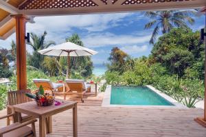 a patio with a table and a swimming pool at Kudafushi Resort & Spa in Raa Atoll