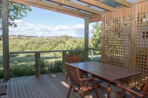 um deque de madeira com uma mesa e cadeiras de madeira em Longford Riverside Caravan Park em Longford