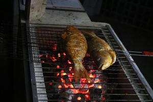 two fish cooking on top of a grill at Sunset Serenity in Jaliapāra