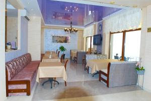 a restaurant with tables and chairs and a couch at Villa Lavanda in Vapnyarka