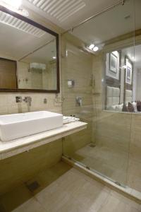 uma casa de banho com um lavatório e uma cabina de duche em vidro. em Hotel Emerald em Chandīgarh
