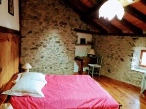 a bedroom with a red bed in a brick wall at Ker Carlines in Targassonne