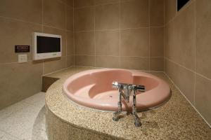 a pink bath tub in a bathroom with a tv at Hotel Birthday Kakamigahara in Kakamigahara