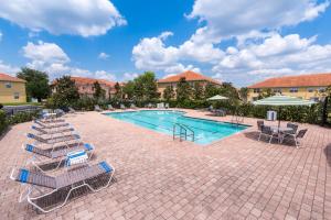 a swimming pool with lounge chairs and umbrellas at Lovely Disney Vacation House in Orlando