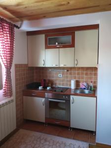 a small kitchen with white cabinets and a sink at Apartments Radingturs in Žabljak