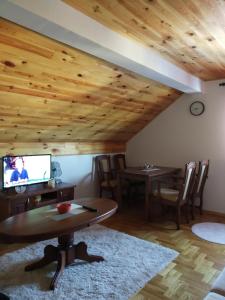 a living room with wooden ceilings and a table and a tv at Apartments Radingturs in Žabljak
