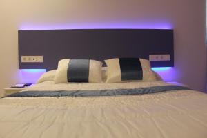 Bilbao Place في بلباو: غرفة نوم مع سرير أبيض كبير مع أضواء أرجوانية