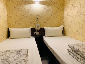 香港Victoria Inn的黄色壁纸客房内的两张床