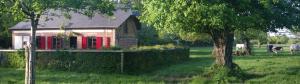 a barn with red doors and a tree in a field at La petite Cauvinière in Saint-Aubin-de-Bonneval +6 photos