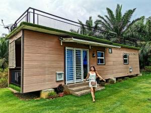 a woman standing in front of a small house at Jeram Tiny House in Jeram