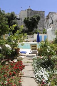 a garden with a bench and flowers and a pool at Palazzo Altavilla in Ostuni