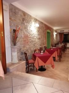 a restaurant with red tables and chairs and a stone wall at Hotel Azzurra in Salsomaggiore Terme