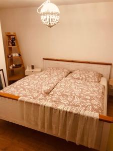 a bed in a bedroom with a chandelier at Soutterain - Wohnung mit Senkgarten in Weingarten (Karlsruhe)