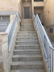un conjunto de escaleras que conducen a un edificio con puerta en Buchman apartment near center, en Modi‘in
