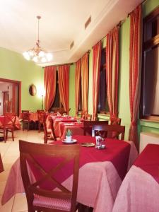 un restaurant avec des tables, des chaises et des rideaux rouges dans l'établissement Hotel Azzurra, à Salsomaggiore Terme