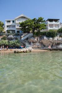 a group of people sitting on the beach near the water at Apartments Agava-Mirjana in Omiš