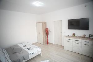 Habitación blanca con cama y TV de pantalla plana. en Apartament LA MAL en Sibiu