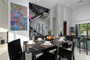 a dining room with a black table and chairs at 3 bed beachfront modern house in Kata Noi in Kata Beach