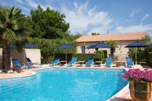 a swimming pool with blue chairs and umbrellas at Top Motel in Istres