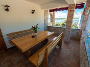 a dining room with a wooden table and benches at Apartments Anita 1 in Barbat na Rabu