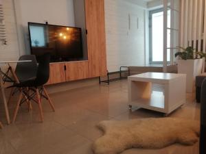 a living room with a tv and a chair and a table at Apartament BeSkidSki in Szczyrk +2 photos
