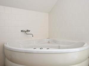 uma banheira branca numa casa de banho com azulejos brancos em 4 star holiday home in Gjern em Gjern