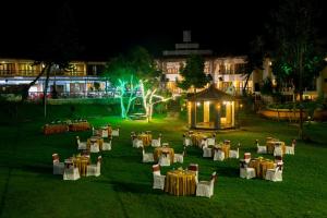a group of tables and chairs in a field at night at Hotel Kodai International in Kodaikānāl